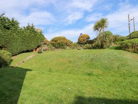 A grassy garden with stone steps leading up to shrubs and bushes at Swn Y Wylan in Bwlchtocyn near Abersoch