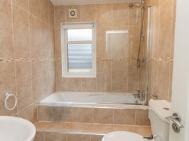 A bathroom with a bath tub, shower, toilet, and sink at The Warren D7 Abersoch