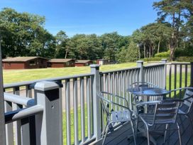 A balcony with a table and chairs overlooking a grassy area with cabins at Lavender Lodge in Saltburn-By-The-Sea