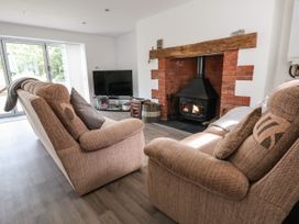 A living room with two beige sofas a television and a brick fireplace at Cae Iocyn in Chirk