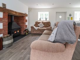 A sitting room with two brown sofas a fireplace with a wood stove and a door at Cae Iocyn in Chirk
