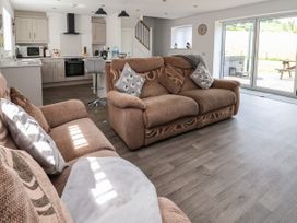 An open plan living room and kitchen with brown sofas and patterned cushions at Cae Iocyn in Chirk
