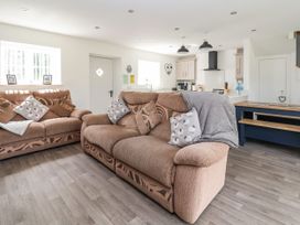 A living room with brown sofas and cushions next to a kitchen and dining area at Cae Iocyn in Chirk