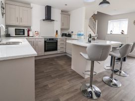 A kitchen with an island and bar stools a microwave oven and cabinets at Cae Iocyn in Chirk