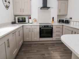 A kitchen with white countertops gray cabinets microwave oven stove kettle and knife block at Cae Iocyn in Chirk