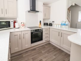 A kitchen with beige cabinets white countertops a black oven microwave toaster kettle and water bottles at Cae Iocyn in Chirk