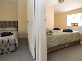 Two bedrooms separated by a white door each with a bed and folded towels on the beds at Cae Iocyn in Chirk