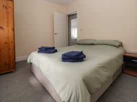 A bedroom with a double bed with green bedding and folded towels on it a wooden wardrobe and a bedside table at Cae Iocyn in Chirk