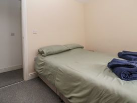 A bedroom with a double bed covered with green bedding and blue towels at Cae Iocyn in Chirk