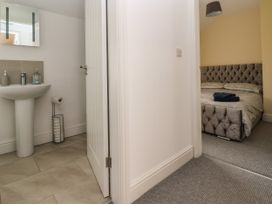 A bathroom with a pedestal sink and a mirror next to a bedroom with a bed and folded towels at Cae Iocyn in Chirk