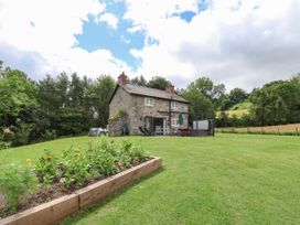 A stone house with outdoor furniture and a flower bed on a lawn at Cae Iocyn in Chirk