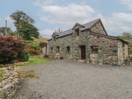 A stone house with gravel driveway and flower pots at Beudy Penarddwnion in Rhydymain near Dolgellau