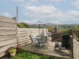 A deck with a table and chairs under an umbrella at Beudy Penarddwnion in Rhydymain near Dolgellau