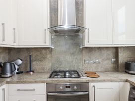 A kitchen with cabinets, stove, kettle and utensils at Kinbrae Apartment in Torquay