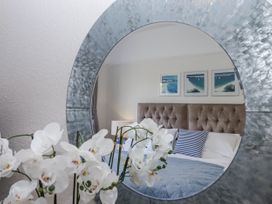 A bedroom with a mirror and flowers at Kinbrae Apartment in Torquay