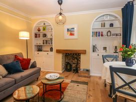A living room with a sofa, bookshelves, and a dining table at 1 Tower House in Cartmel