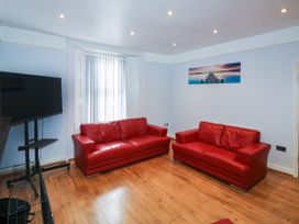 A living room with two red sofas a wall mounted television and a window with blinds at 11 Magdalene Road in Torquay