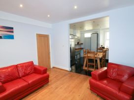 A living room with two red sofas and a dining area with wooden table and chairs at 11 Magdalene Road in Torquay