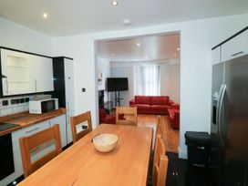A kitchen and dining area with a wooden table and chairs a microwave on the counter and a living room with red sofas and a television at 11 Magdalene Road in Torquay