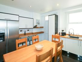 A kitchen with wooden table and chairs stainless steel refrigerator white cabinets and a sink at 11 Magdalene Road in Torquay