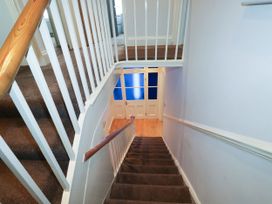 A staircase with brown carpet leading down to a set of white double doors with blue window panels at 11 Magdalene Road in Torquay