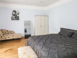 A bedroom with a bed covered in a dark quilt a floral patterned sofa a white wardrobe and a full length mirror at 11 Magdalene Road in Torquay