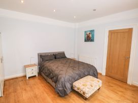 A bedroom with a double bed with gray bedding two bedside tables a wooden door a radiator and a small patterned ottoman at 11 Magdalene Road in Torquay
