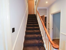 A carpeted staircase with wooden handrail leading to a closed wooden door at 11 Magdalene Road Torquay