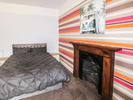 A bedroom with a bed a wooden fireplace and striped wallpaper at 11 Magdalene Road in Torquay