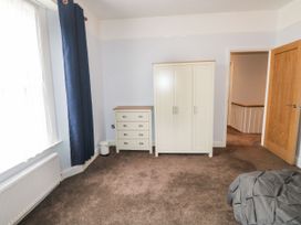 A bedroom with a wardrobe chest of drawers blue curtains and a window at 11 Magdalene Road Torquay