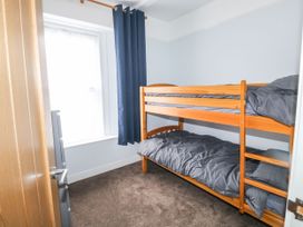 A bedroom with a wooden bunk bed next to a window with blue curtains at 11 Magdalene Road in Torquay