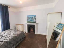 A bedroom with a bed dresser wardrobe mirror and a fireplace at 11 Magdalene Road in Torquay
