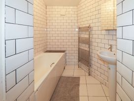 A bathroom with a bathtub a sink and a towel radiator at 11 Magdalene Road in Torquay