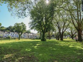 A grassy park area with large trees and houses in the background at 11 Magdalene Road in Torquay