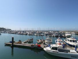 A marina with multiple boats and yachts docked at wooden piers under a clear sky at 11 Magdalene Road in Torquay