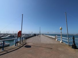 A wooden pier with benches and lamp posts overlooking boats and the sea at 11 Magdalene Road in Torquay