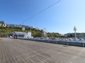 A wooden boardwalk with lamp posts and a Ferris wheel near buildings on a hillside at 11 Magdalene Road in Torquay