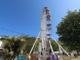 A Ferris wheel in a park area with trees and buildings on a hill at 11 Magdalene Road in Torquay