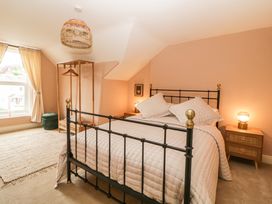 A bedroom with a black metal bed frame two bedside tables with lamps a window with curtains a woven hanging light and an open wooden clothes rack at Midhurst in Brixham