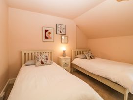 A bedroom with two single beds a nightstand with a lamp and three framed pictures on the wall at Midhurst in Brixham