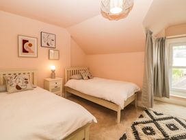 A bedroom with two single beds bedside table lamp framed pictures and a window with curtains at Midhurst in Brixham