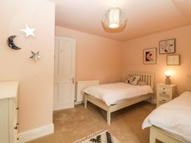A bedroom with two single beds a nightstand with a lamp wall art and star and moon mirrors at Midhurst in Brixham