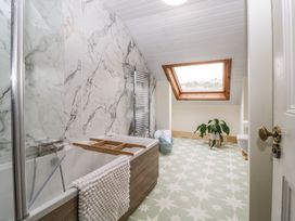 A bathroom with a bathtub towel radiator skylight window plant and patterned floor at Midhurst in Brixham