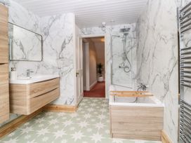 A bathroom with a bathtub shower combination and wooden cabinets at Midhurst in Brixham