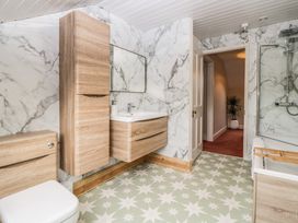 A bathroom with wood cabinets a toilet a sink a bathtub a shower and patterned floor tiles at Midhurst in Brixham