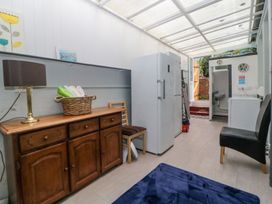 A utility room with a wooden sideboard lamp basket towels fridge chairs and a washing machine at Midhurst in Brixham