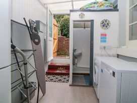 A utility room with a washing machine dryer ironing board and open door leading outside at Midhurst in Brixham