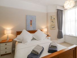 A bedroom with a wooden bed and white bedding with towels on the bed two bedside tables with lamps and framed pictures on the walls at Midhurst in Brixham