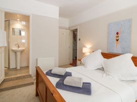 A bedroom with a wooden bed frame white bedding towels on bed a lamp and painting on wall at Midhurst in Brixham