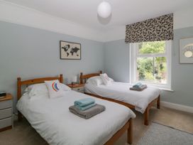A bedroom with two single beds with white bedding and wooden frames at Midhurst in Brixham